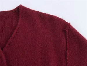 Detail eines burgunderfarbenen Strickpullovers mit flauschiger Textur und V-Ausschnitt
