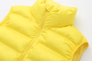 Détail du col montant et du zip sur un gilet matelassé léger de couleur jaune vif