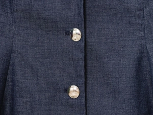 Close-up of silver metal buttons and twill texture on dark blue denim vest fabric