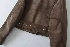 Detail view of the deep brown faux suede jacket hem featuring metallic silver eyelet belt accents