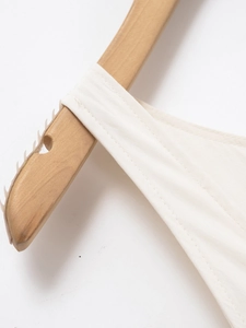 Detail view of double-stitched shoulder strap and seams on a white linen dress