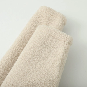 Gros plan sur la texture sherpa beige d'un sweat à capuche court en polaire pour femme