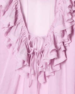 Detailed view of ruffle V-neck and adjustable tie on light pink long sleeve shirt