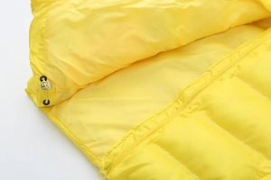 Détail macro du gilet matelassé jaune avec système de zip et cordon de serrage