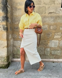 Close-up of yellow striped long sleeve shirt styled with beige slit denim skirt