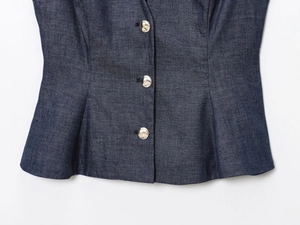 Close-up of slim fit dark blue denim vest with silver metal buttons and waist darts