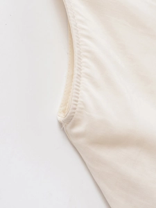 Macro detail of high-quality stitching and cotton-linen texture on a cream backless dress