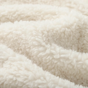 Close-up macro of white faux shearling fabric showing soft curly texture and warm wooly fibers