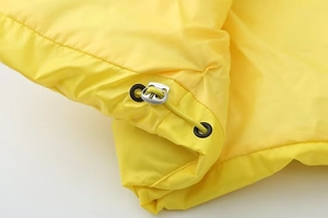Détail macro du gilet coupe-vent jaune vif avec cordons de serrage en métal argenté