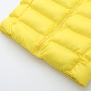 Détail macro de la veste matelassée jaune vif avec coutures horizontales et zip assorti