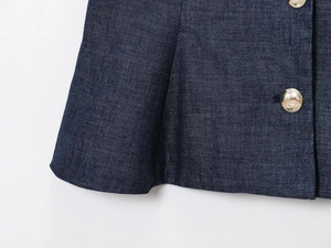 Close-up of dark blue denim fabric with polished gold metal buttons and neat stitching