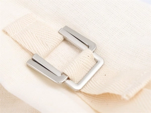 Detail of silver metal buckle and beige canvas strap on a minimalist casual jacket