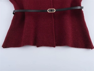 Detail von burgunderfarbenem Strickstoff mit schmalem schwarzem Ledergürtel und Goldschnalle