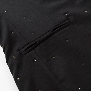 Detailansicht des schwarzen Blazers mit schimmernden Strasssteinen und Leistentasche