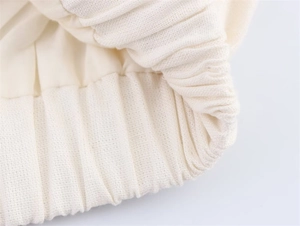 Close-up of elastic ribbed cuff and premium knit fabric on off-white spring jacket