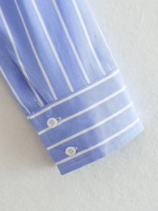 Detailed close-up of blue and white vertical striped shirt cuff with two white buttons