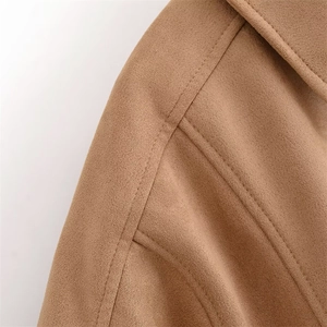 Gros plan des doubles coutures et de la texture en daim sur l'épaule de la veste