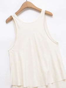 Detail of a beige sleeveless tank top with a layered hem on a wooden hanger