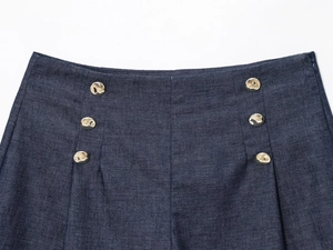 Detail of dark blue high-waisted denim shorts with six decorative gold buttons