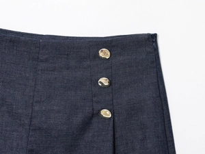 Detail of high-waisted navy linen shorts with side zipper and three gold decorative buttons