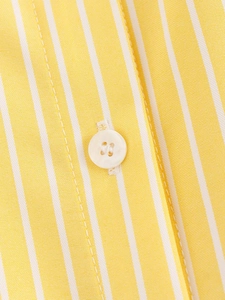 Macro shot of yellow and white striped fabric with detail of a white resin button