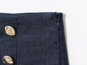 Detail of dark blue denim shorts with invisible side zipper and gold metal buttons