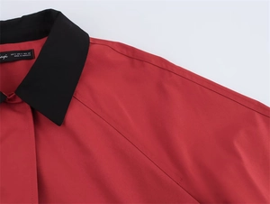 Detail eines kontrastierenden schwarzen Kragens an einer ziegelroten Damenbluse