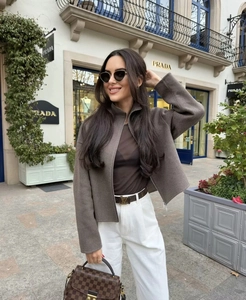 Detail view of a brown stand-collar wool jacket styled with a designer belt and handbag