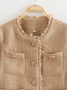 Detail of tweed jacket with frayed edges and golden woven buttons on pockets