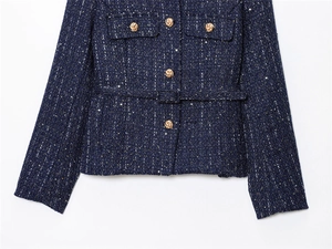 Macro detail of dark blue tweed jacket texture featuring ornate gold embossed buttons