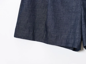 Detailed close-up of dark blue denim fabric texture and fine stitching on summer shorts