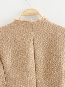Detail of the frayed edge neckline on this camel tweed jacket with textured fabric weave