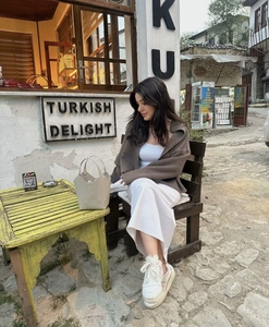 Outdoor street style of a brown wool jacket paired with a white long skirt and bucket bag