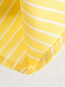 Macro detail of yellow and white striped cotton shirt fabric with neat stitching