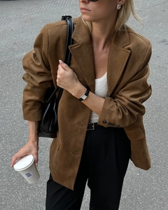 Close-up of a premium black leather shoulder bag paired with a brown suede blazer coat