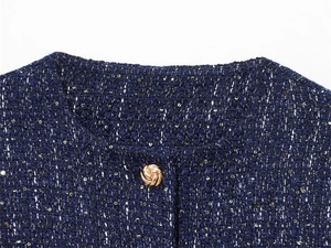 Close-up of navy tweed jacket neckline with gold sequins and textured metal button