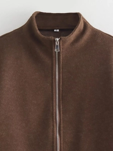 Detail of metal zipper and S-size label on dark brown fleece jacket with stand collar