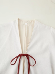 Close-up of beige cotton-linen fabric with deep V-neck and red drawstring ties