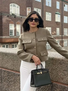 Dettaglio dell'elegante giacca in tweed kaki con bottoni dorati e quattro tasche a pattina
