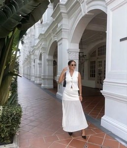 Close-up of white V-neck vest with gold buttons and pleated tulle skirt set in sunny arcade