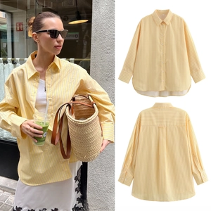 Detail of yellow striped poplin shirt showing buttoned cuffs and curved high-low hemline