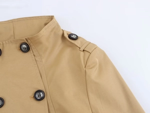 Detail of khaki trench coat featuring shoulder epaulettes and classic brown buttons