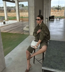 Fashionable model posing in olive green utility jacket with white crescent leather hobo bag