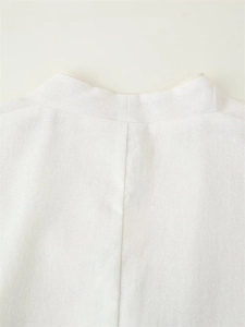 Macro detail of white linen V-neck jacket showing neat back seam and fabric texture