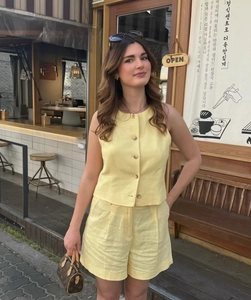 Detail eines hellgelben Leinen-Sets mit Weste zum Knöpfen und Shorts mit hohem Bund