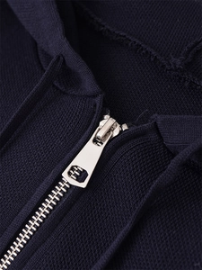 Détail macro de la fermeture éclair en métal argenté sur une veste en maille bleu foncé