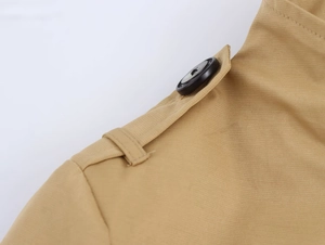 Detailed view of khaki trench coat shoulder epaulet with a black round button