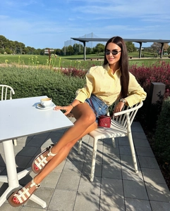 Detail of yellow striped poplin shirt paired with denim shorts and a red leather bag