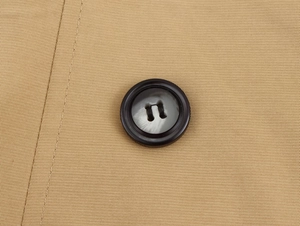 Macro shot of marble textured button and neat stitching on khaki double-breasted trench coat