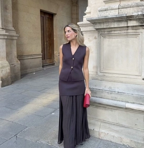 Detail of elegant chocolate brown V-neck knit vest with gold buttons and pleated skirt